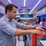 Gestor de papelaria reposicionando produtos na altura dos olhos em uma gôndola de material escolar